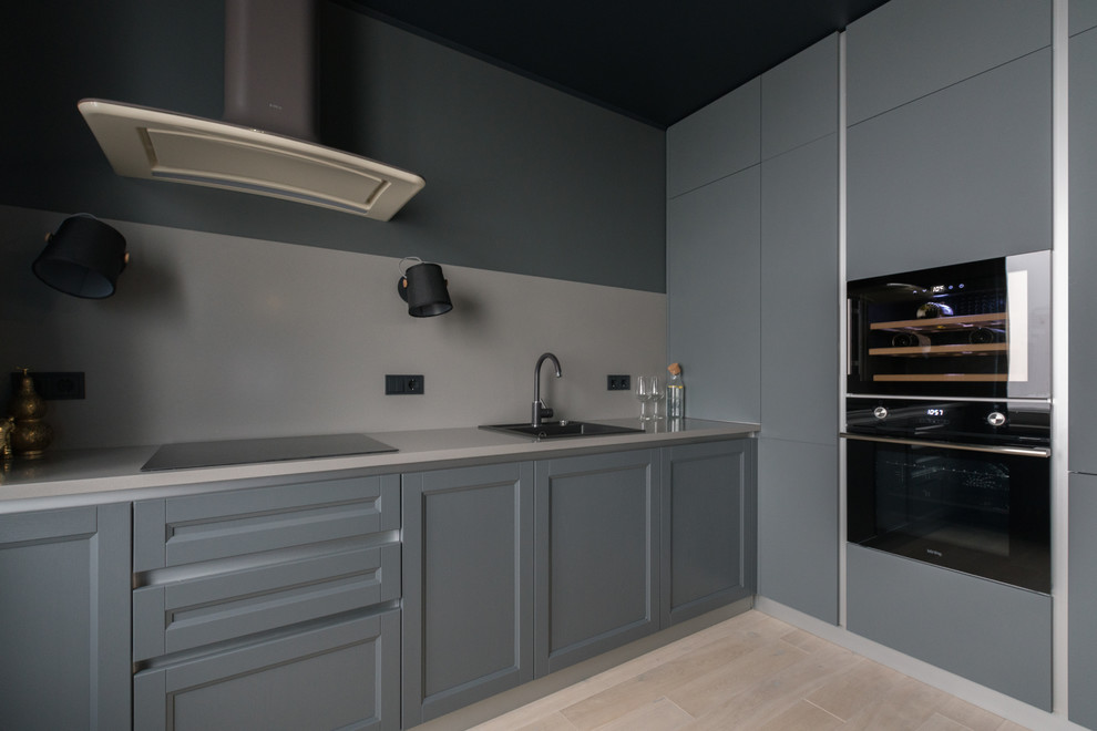Exempel på ett mellanstort modernt grå grått kök, med en nedsänkt diskho, luckor med infälld panel, grå skåp, bänkskiva i kvarts, grått stänkskydd, svarta vitvaror, mellanmörkt trägolv och beiget golv
