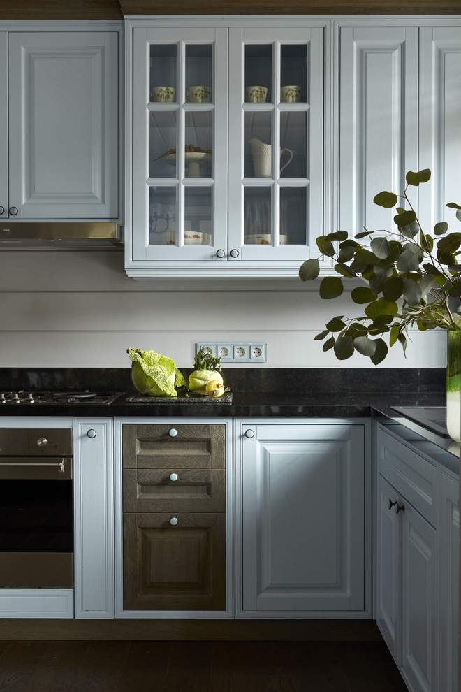 Foto di una cucina classica con lavello da incasso, ante con bugna sagomata, top nero, top in granito, parquet scuro e pavimento marrone