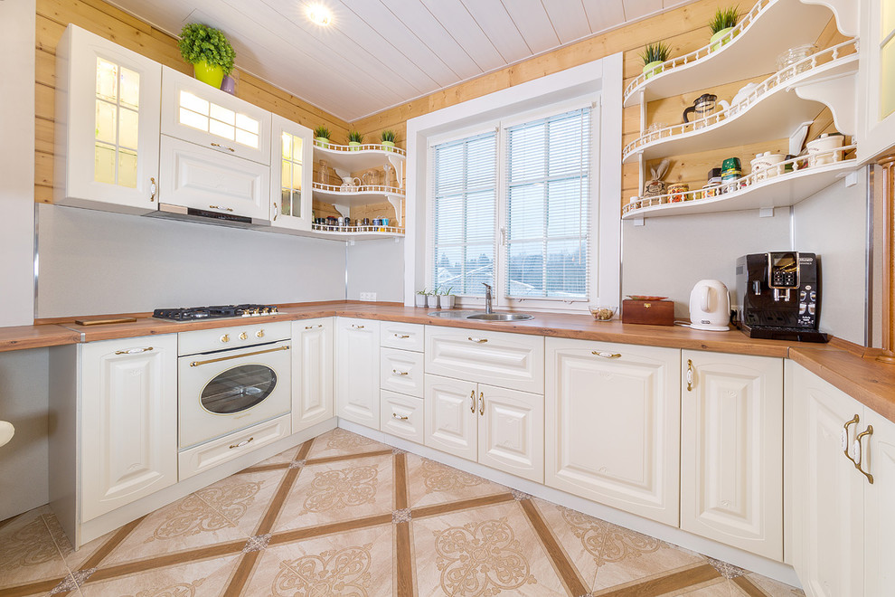 Inspiration for a small transitional u-shaped eat-in kitchen remodel in Saint Petersburg with a drop-in sink, recessed-panel cabinets, white cabinets, wood countertops and no island