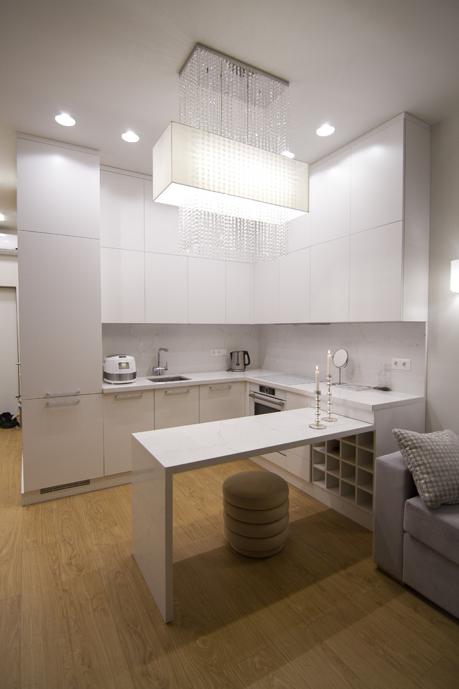 Inspiration for a medium sized contemporary u-shaped open plan kitchen in Moscow with a single-bowl sink, flat-panel cabinets, white cabinets, engineered stone countertops, white splashback, stone slab splashback, white appliances, light hardwood flooring, a breakfast bar, brown floors and white worktops.