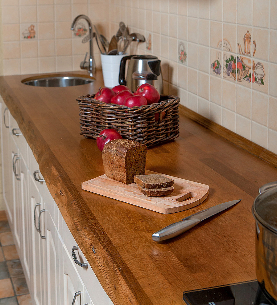 Bild på ett mellanstort rustikt linjärt kök och matrum, med en undermonterad diskho, luckor med upphöjd panel, beige skåp, träbänkskiva, beige stänkskydd, stänkskydd i keramik, färgglada vitvaror och klinkergolv i keramik