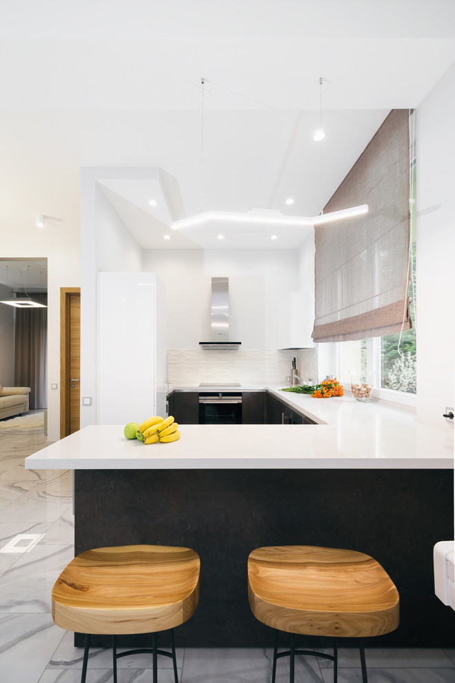 На фото: отдельная, угловая кухня в современном стиле с плоскими фасадами, серыми фасадами, белым фартуком, полуостровом и серым полом