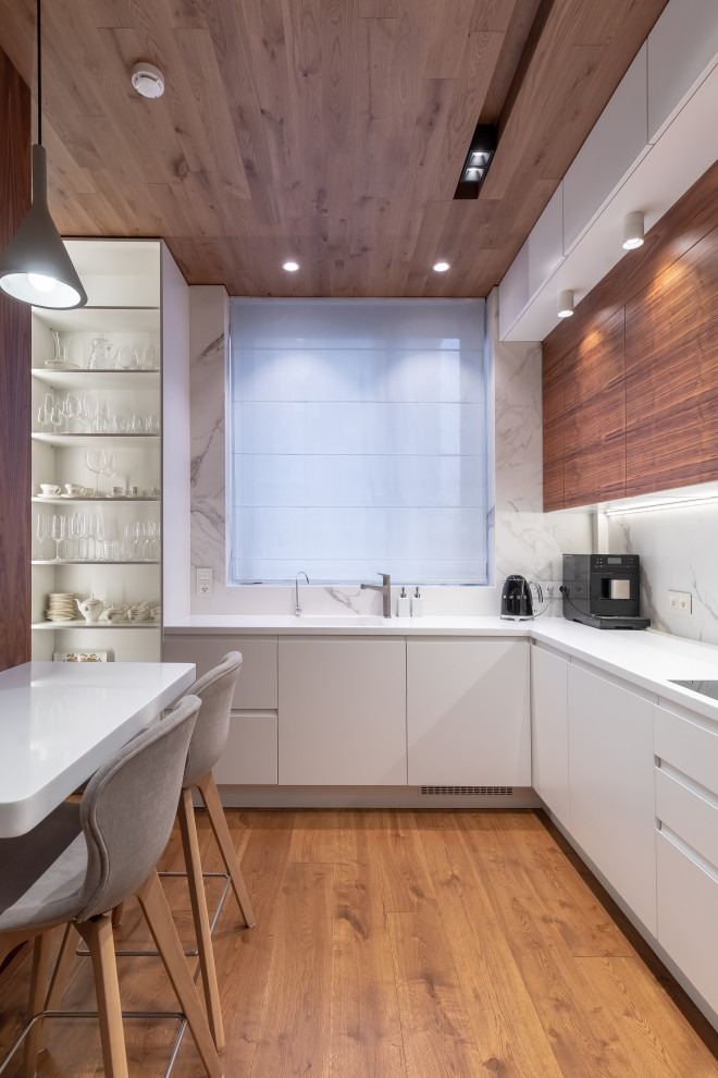 Contemporary l-shaped enclosed kitchen in Moscow with an integrated sink, flat-panel cabinets, white cabinets, white splashback, integrated appliances, medium hardwood flooring, brown floors and white worktops.