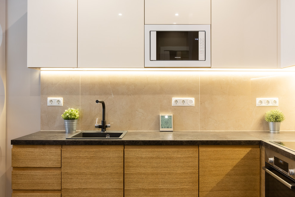 This is an example of a medium sized contemporary l-shaped kitchen/diner in Moscow with a submerged sink, flat-panel cabinets, white cabinets, composite countertops, beige splashback, porcelain splashback, black appliances, porcelain flooring, no island, black floors and black worktops.