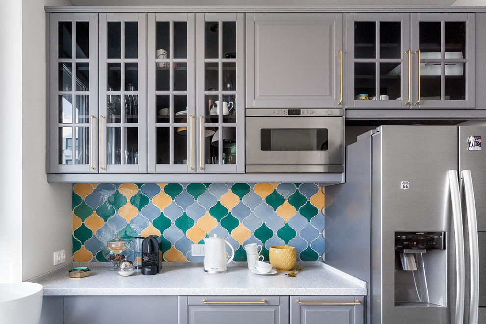 Small world-inspired galley kitchen/diner in Moscow with a belfast sink, beaded cabinets, white cabinets, composite countertops, multi-coloured splashback, ceramic splashback, stainless steel appliances, ceramic flooring, no island, beige floors and white worktops.