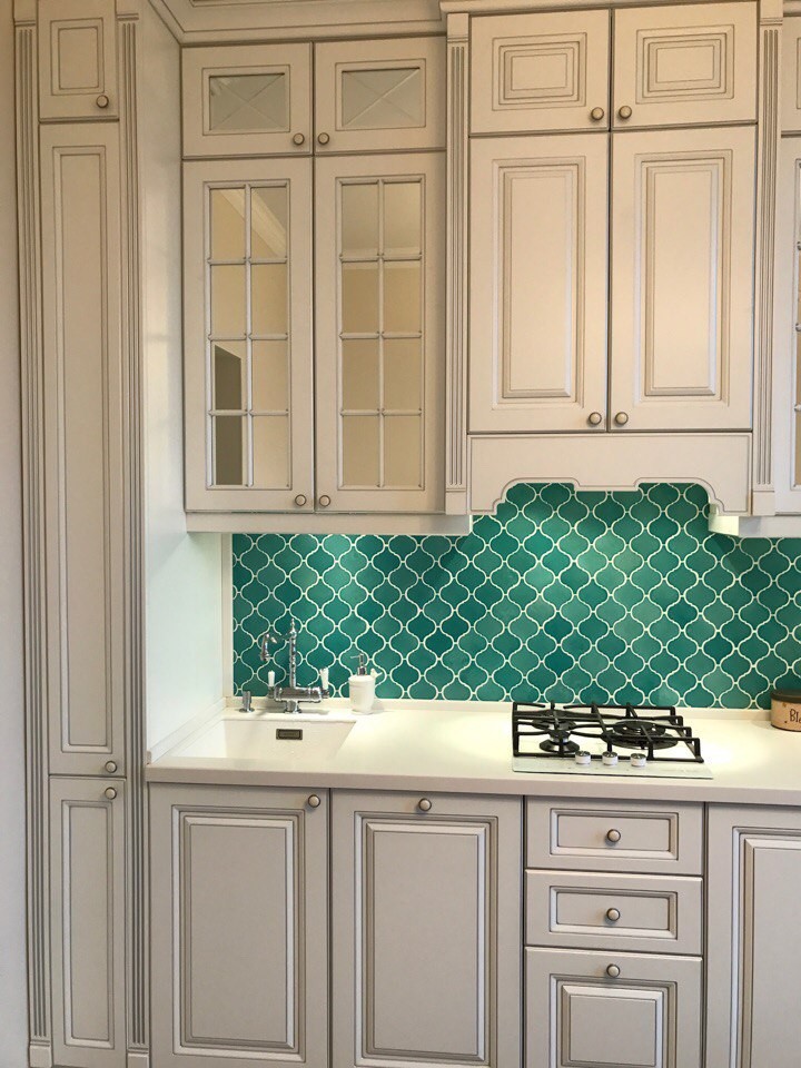Bild på ett avskilt, litet vintage vit linjärt vitt kök, med en undermonterad diskho, luckor med infälld panel, vita skåp, bänkskiva i koppar, grönt stänkskydd, stänkskydd i mosaik, vita vitvaror, laminatgolv och grått golv
