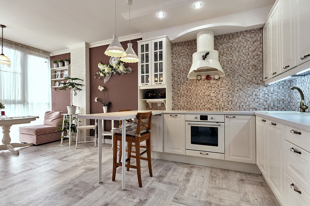 Offene Moderne Küche in L-Form mit weißen Schränken, Küchenrückwand in Beige, Rückwand aus Mosaikfliesen, weißen Elektrogeräten, hellem Holzboden und Halbinsel in Sonstige