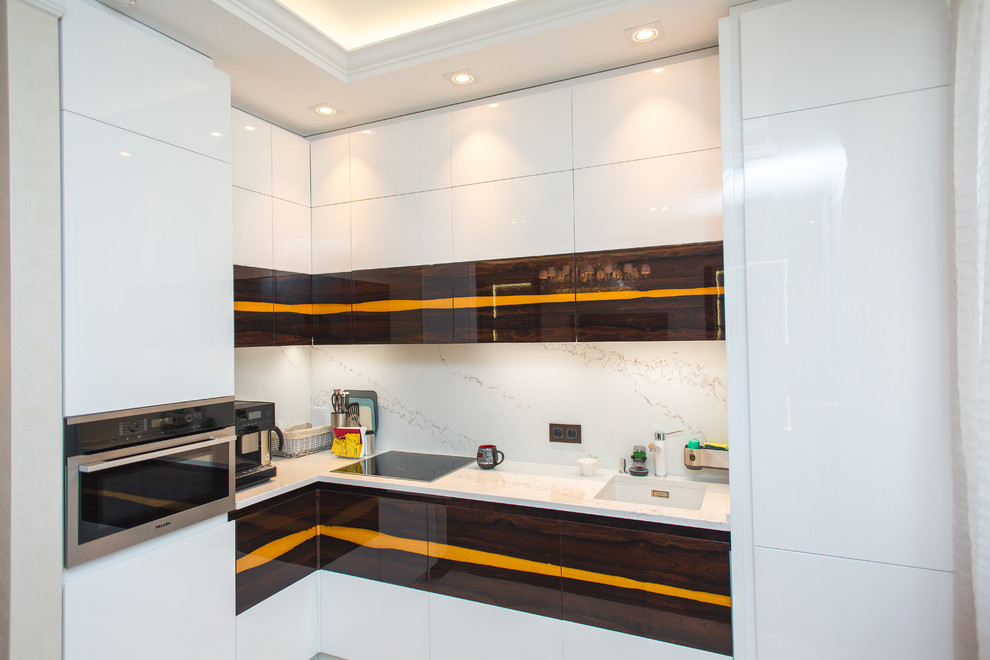 Diseño de cocinas en L contemporánea con fregadero bajoencimera, armarios con paneles lisos, puertas de armario blancas, salpicadero blanco, electrodomésticos de acero inoxidable y encimeras blancas