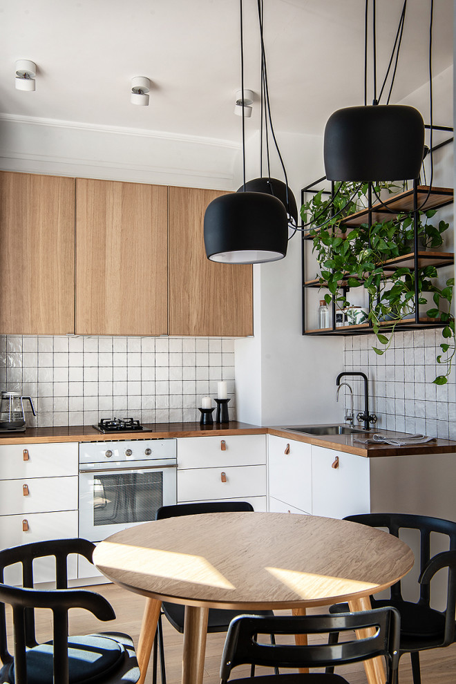 Идея дизайна: угловая, светлая кухня-гостиная в скандинавском стиле с плоскими фасадами, белыми фасадами, белым фартуком, белой техникой, светлым паркетным полом, бежевым полом и коричневой столешницей без острова