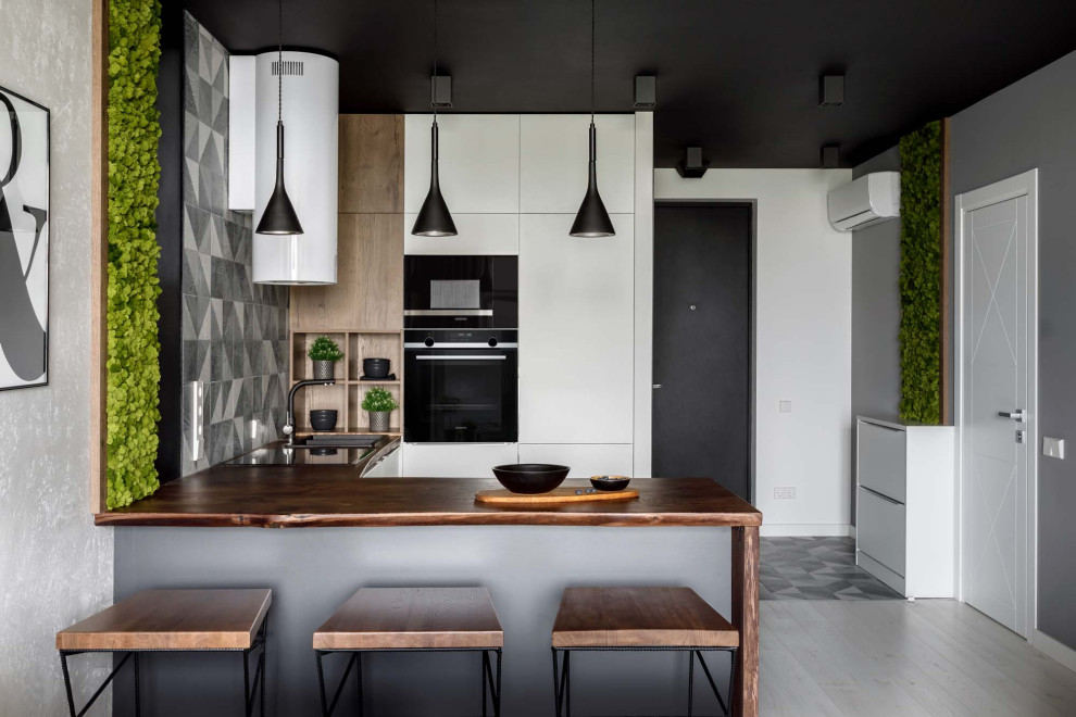 На фото: кухня в скандинавском стиле с плоскими фасадами, серым фартуком и коричневой столешницей