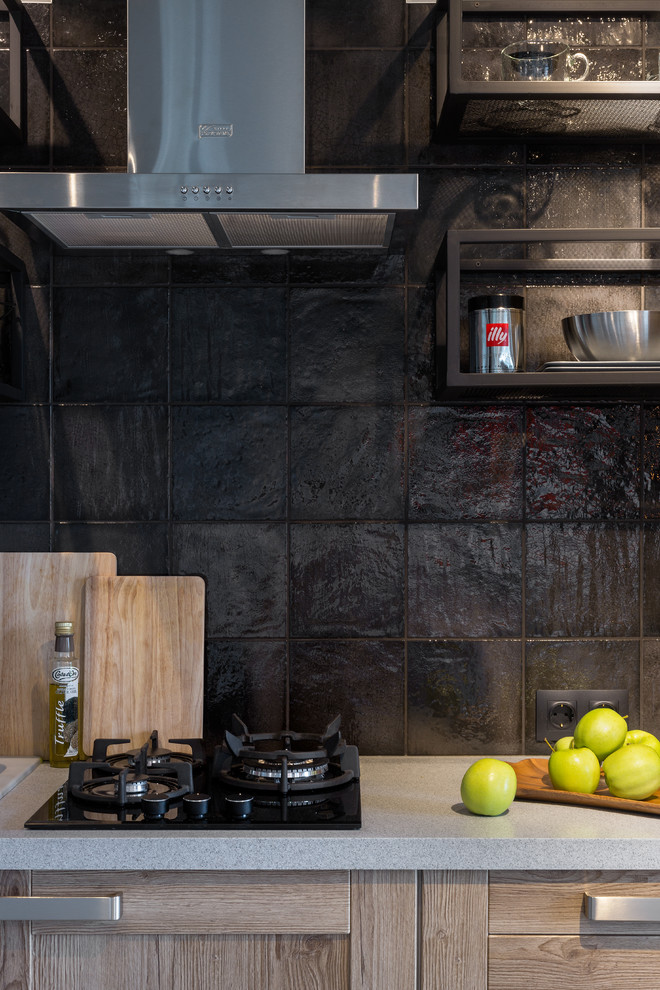 Réalisation d'une cuisine linéaire urbaine en bois clair de taille moyenne avec un plan de travail en surface solide, une crédence noire et une crédence en céramique.