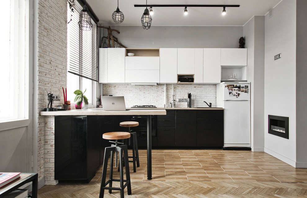 Стильный дизайн: кухня-гостиная среднего размера в стиле лофт с плоскими фасадами, черной техникой и коричневым полом без острова - последний тренд