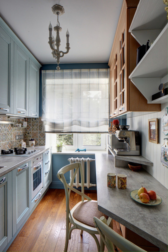 Photo of a small contemporary galley enclosed kitchen in Moscow with a built-in sink, laminate countertops, multi-coloured splashback, ceramic splashback, white appliances, medium hardwood flooring, no island and blue cabinets.
