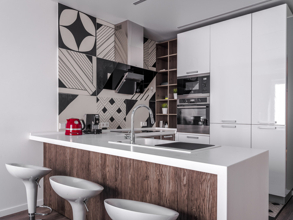 Medium sized contemporary u-shaped kitchen/diner in Moscow with flat-panel cabinets, white cabinets, composite countertops, porcelain splashback, a built-in sink, stainless steel appliances, a breakfast bar, white worktops, multi-coloured splashback and a feature wall.