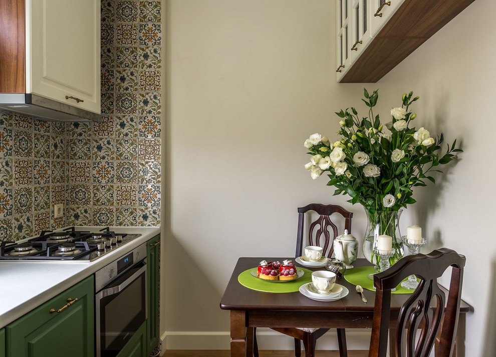 Inspiration för avskilda, små klassiska l-kök, med luckor med upphöjd panel, gröna skåp, laminatbänkskiva, stänkskydd i keramik, rostfria vitvaror, mellanmörkt trägolv och flerfärgad stänkskydd