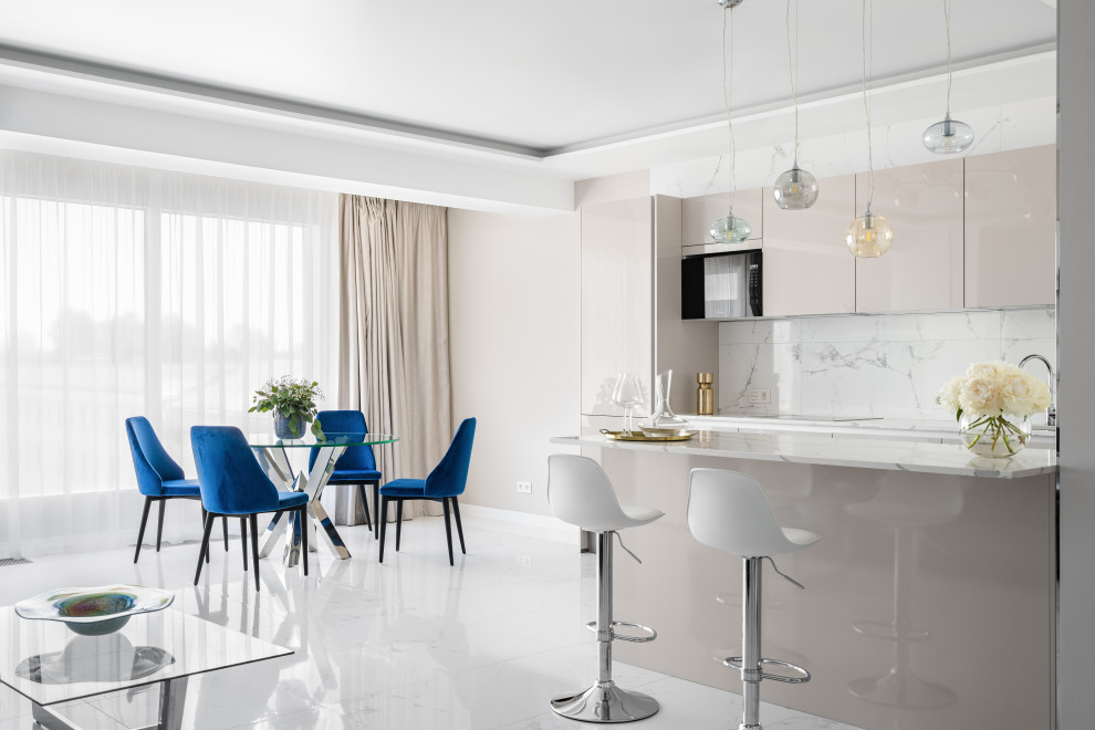 Large contemporary single-wall open plan kitchen in Saint Petersburg with an undermount sink, flat-panel cabinets, beige cabinets, quartz benchtops, white splashback, porcelain splashback, black appliances, porcelain floors, with island, white floor, white benchtop and recessed.