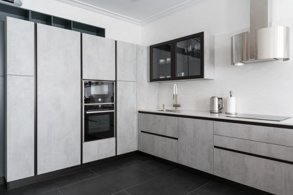 Design ideas for a contemporary l-shaped kitchen in Saint Petersburg with a submerged sink, flat-panel cabinets, grey cabinets, white splashback, black appliances, no island, black floors and white worktops.