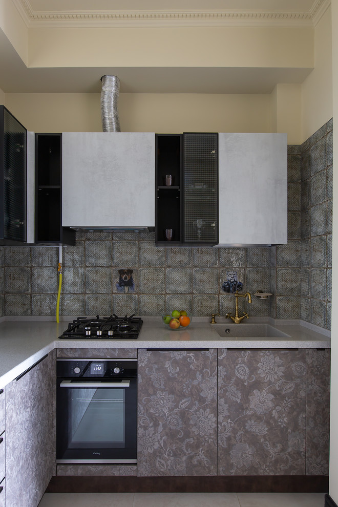 Idee per una cucina a L design con lavello integrato, ante lisce, ante grigie, paraspruzzi grigio, elettrodomestici neri, pavimento grigio e top grigio