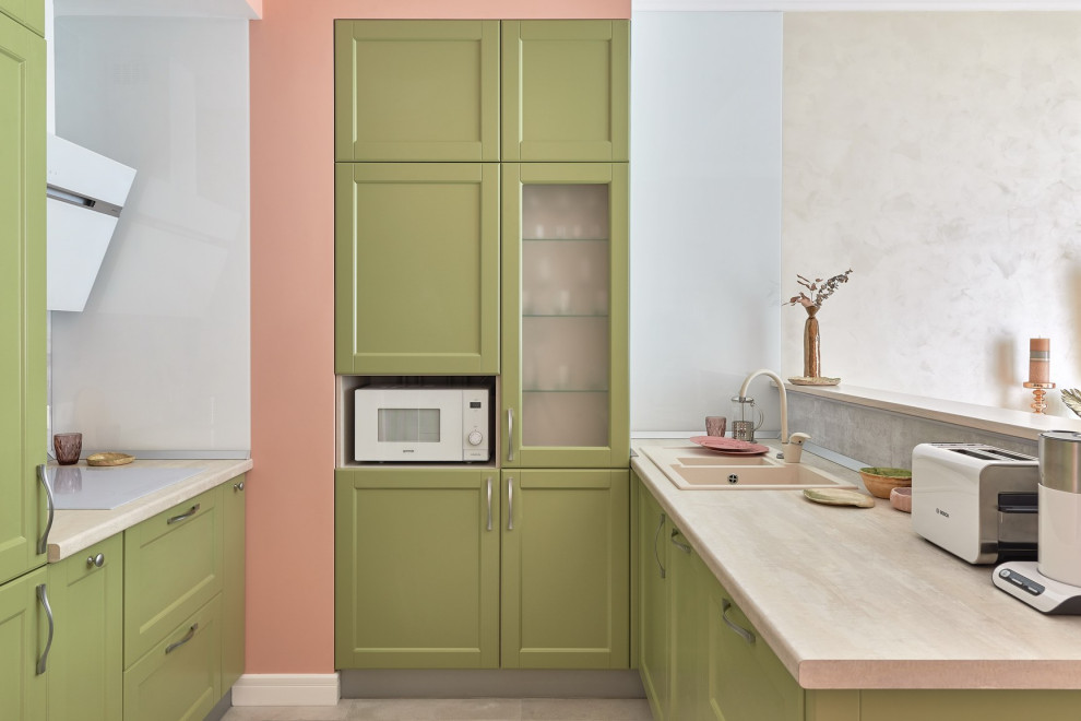 This is an example of a scandi u-shaped open plan kitchen in Other with a built-in sink, shaker cabinets, green cabinets, a breakfast bar, beige floors and beige worktops.