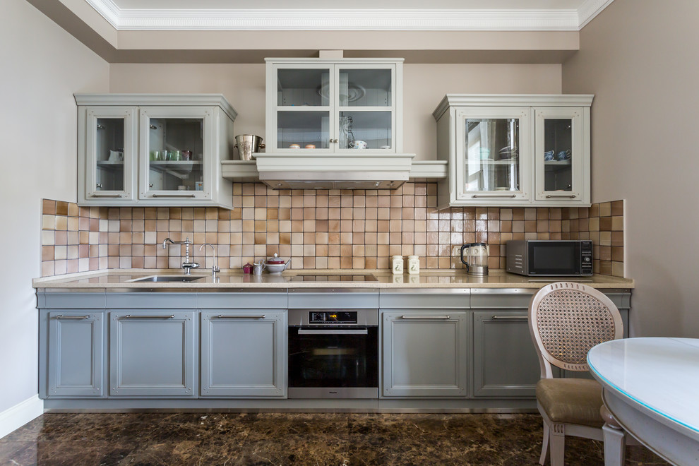 Esempio di una cucina lineare tradizionale chiusa con lavello sottopiano, ante grigie, paraspruzzi beige, elettrodomestici in acciaio inossidabile e nessuna isola
