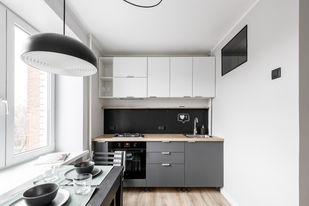Design ideas for a small contemporary single-wall kitchen/diner in Saint Petersburg with a submerged sink, flat-panel cabinets, grey cabinets, laminate countertops, black splashback, stainless steel appliances, laminate floors, brown floors and brown worktops.