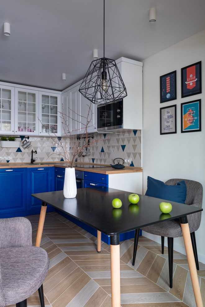 Стильный дизайн: угловая кухня среднего размера в современном стиле с обеденным столом, накладной мойкой, фасадами с выступающей филенкой, столешницей из ламината, разноцветным фартуком, фартуком из керамической плитки, полом из керамогранита, бежевым полом, бежевой столешницей и синими фасадами - последний тренд