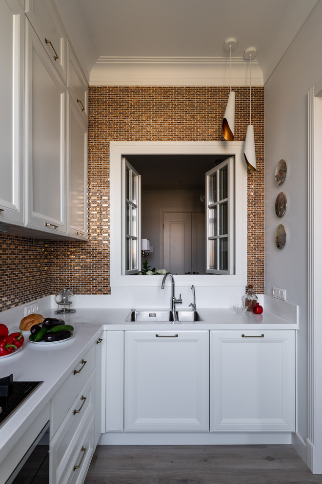Example of a mid-sized transitional l-shaped laminate floor and beige floor enclosed kitchen design in Moscow with an undermount sink, raised-panel cabinets, white cabinets, solid surface countertops, yellow backsplash, mosaic tile backsplash, stainless steel appliances and white countertops