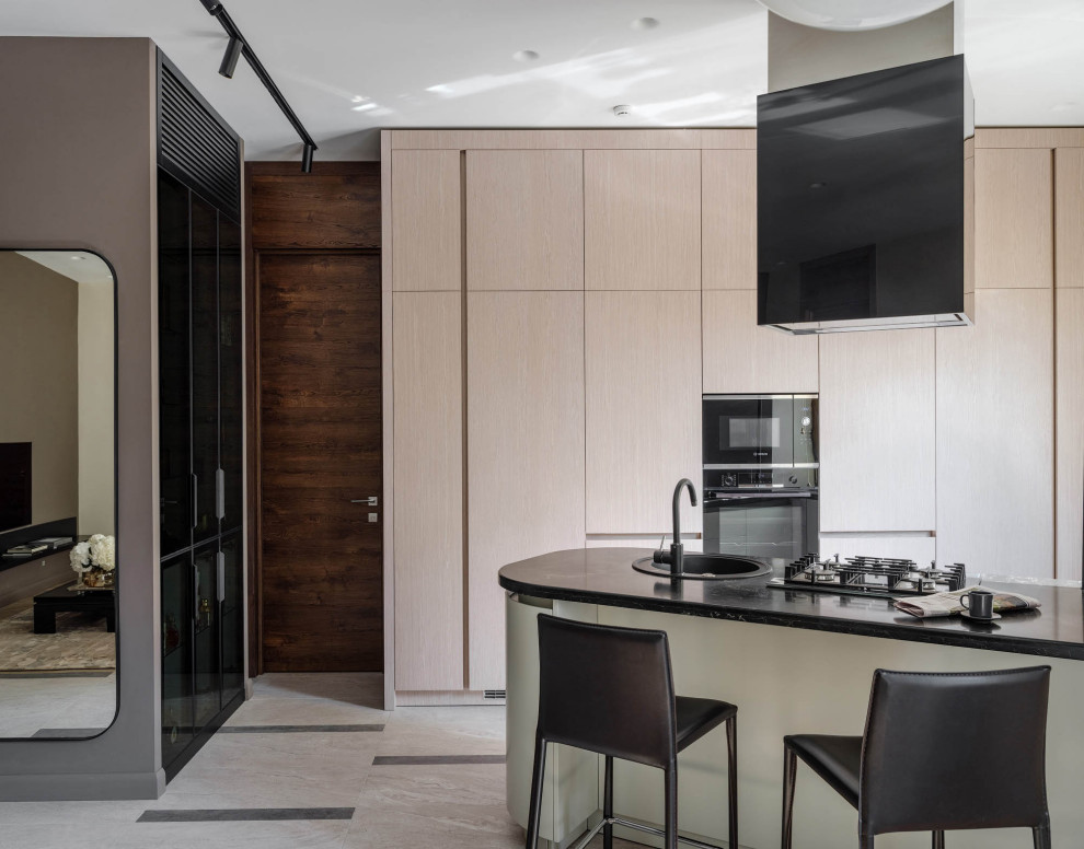 Foto de cocina contemporánea abierta con fregadero encastrado, armarios con paneles lisos, puertas de armario beige, península, suelo beige y encimeras negras