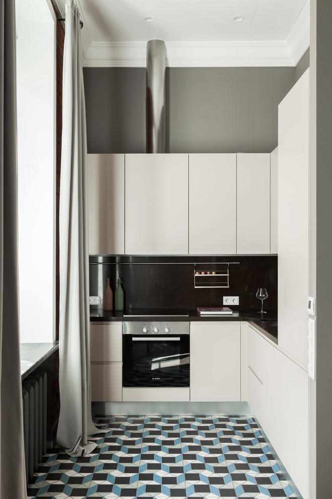 Foto på ett funkis kök, med en enkel diskho, släta luckor, vita skåp, bänkskiva i kvarts, klinkergolv i porslin, svart stänkskydd, rostfria vitvaror och flerfärgat golv