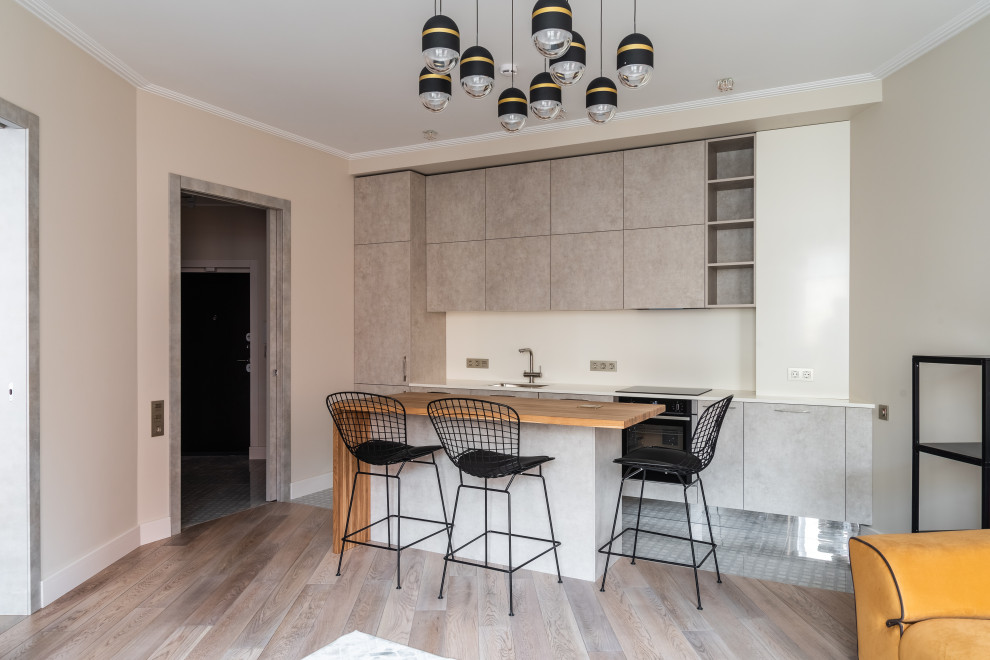 Идея дизайна: прямая кухня-гостиная в современном стиле с врезной мойкой, плоскими фасадами, серыми фасадами, белым фартуком и островом