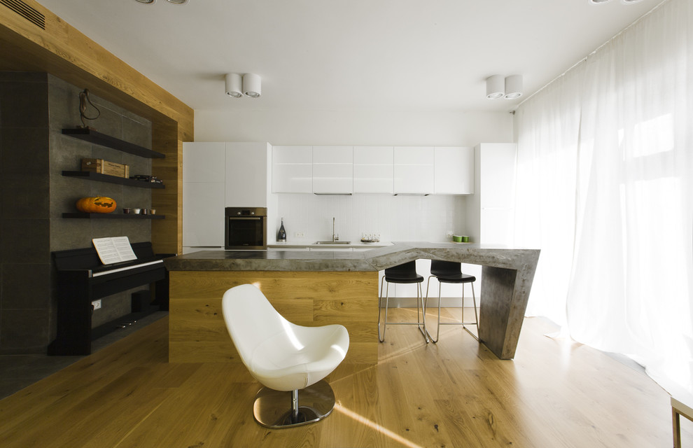 Идея дизайна: прямая кухня-гостиная в современном стиле с плоскими фасадами, белыми фасадами, белым фартуком, техникой из нержавеющей стали, паркетным полом среднего тона и островом