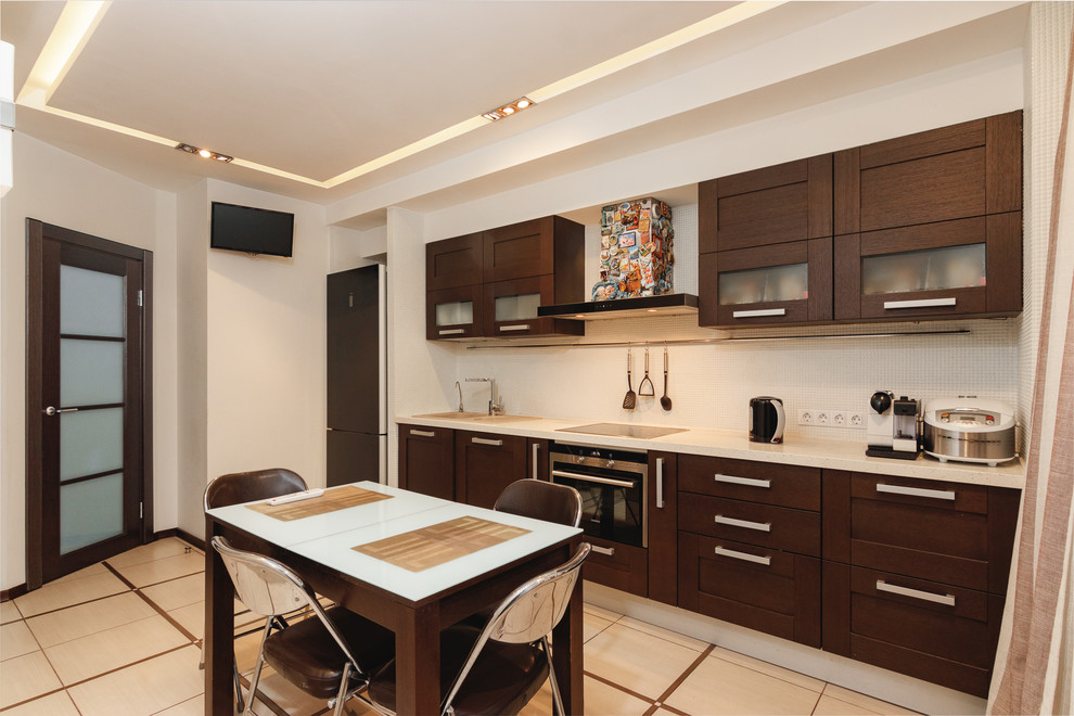 Example of a mid-sized trendy single-wall ceramic tile and beige floor enclosed kitchen design in Saint Petersburg with shaker cabinets, brown cabinets, marble countertops, white backsplash, mosaic tile backsplash, stainless steel appliances, no island, beige countertops and an undermount sink