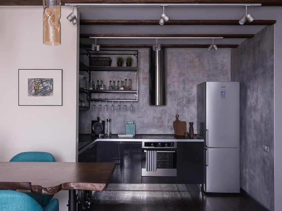 Пример оригинального дизайна: угловая кухня-гостиная в современном стиле с накладной мойкой, плоскими фасадами, черными фасадами, серым фартуком, техникой из нержавеющей стали, темным паркетным полом и коричневым полом без острова