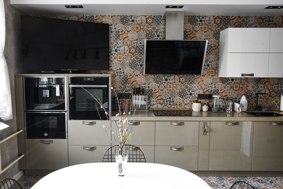 Photo of a small contemporary single-wall kitchen/diner in Moscow with a submerged sink, flat-panel cabinets, beige cabinets, composite countertops, multi-coloured splashback, terracotta splashback, black appliances, terracotta flooring and multi-coloured floors.