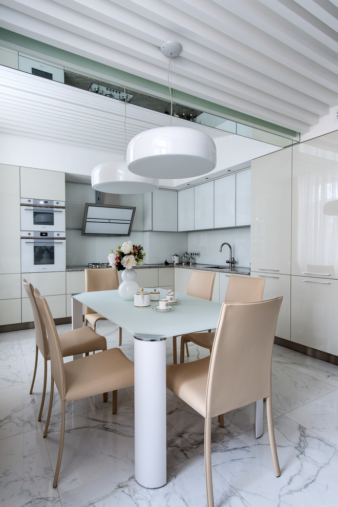 Example of a mid-sized trendy l-shaped ceramic tile and white floor eat-in kitchen design in Moscow with an undermount sink, flat-panel cabinets, gray cabinets, granite countertops, white backsplash, glass sheet backsplash, white appliances, no island and gray countertops