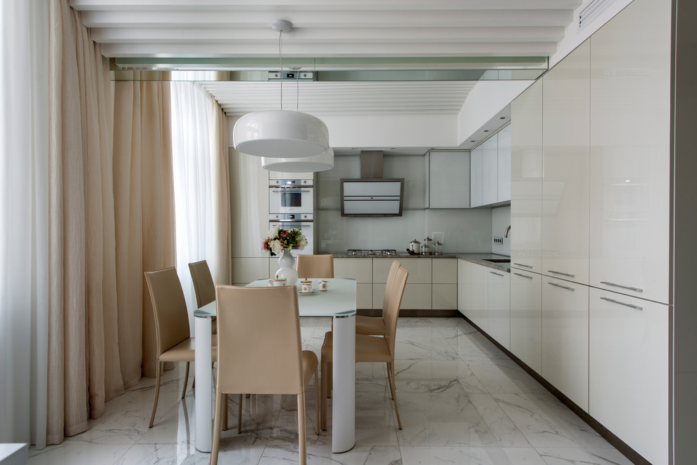 Foto på ett stort funkis kök, med en undermonterad diskho, grå skåp, granitbänkskiva, vitt stänkskydd, glaspanel som stänkskydd, vita vitvaror, marmorgolv och släta luckor