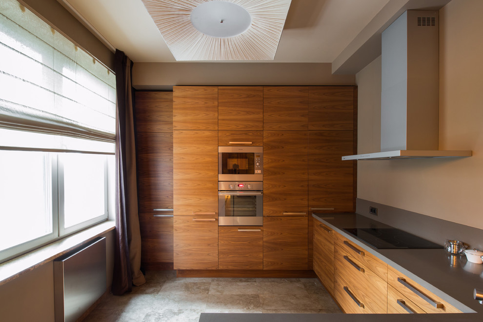 На фото: п-образная кухня-гостиная в современном стиле с плоскими фасадами, фасадами цвета дерева среднего тона, техникой из нержавеющей стали, серым полом и серой столешницей