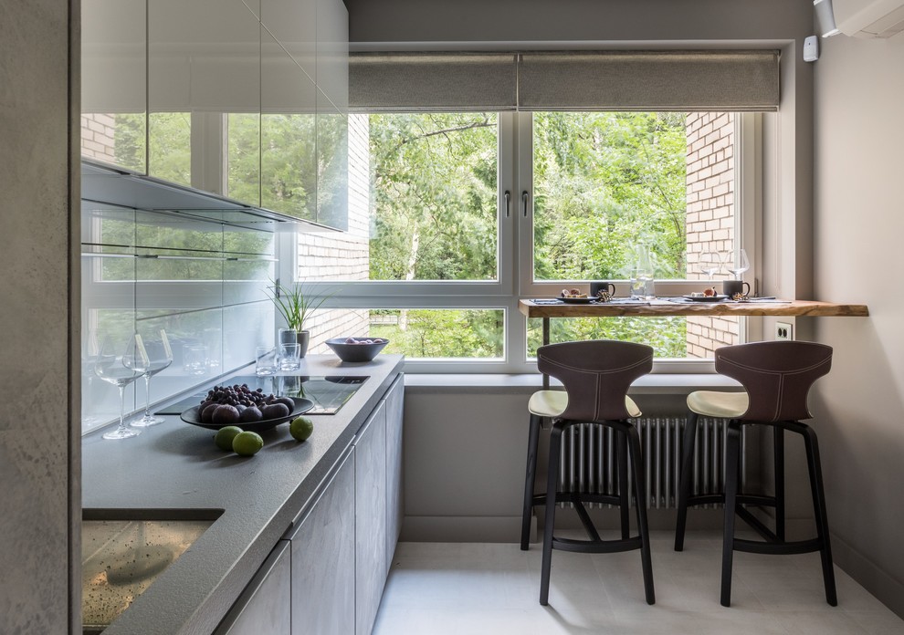 Foto di una cucina lineare minimal di medie dimensioni e chiusa con lavello sottopiano, ante lisce, ante grigie, paraspruzzi bianco, pavimento bianco e nessuna isola