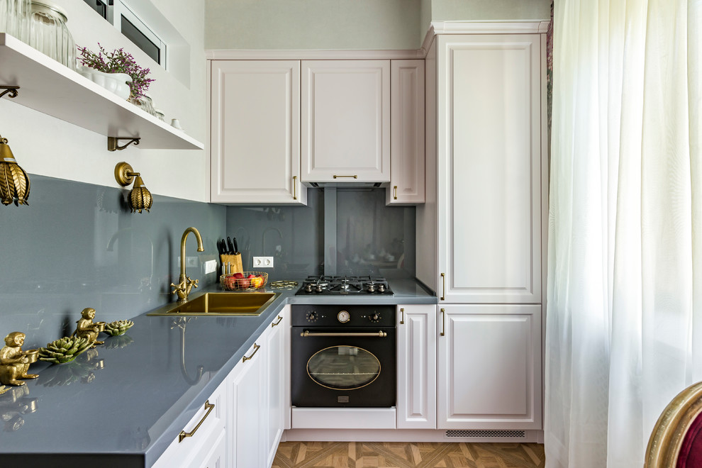 Photo of a small classic l-shaped enclosed kitchen in Moscow with composite countertops, grey splashback, black appliances, porcelain flooring, no island, brown floors, grey worktops, a built-in sink, raised-panel cabinets and white cabinets.