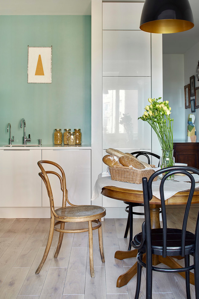 На фото: отдельная кухня в скандинавском стиле с плоскими фасадами, белыми фасадами, светлым паркетным полом, бежевым полом и белой столешницей без острова