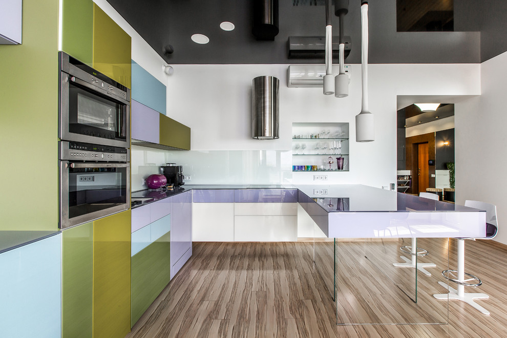На фото: п-образная кухня в современном стиле с обеденным столом, плоскими фасадами, фиолетовыми фасадами, техникой из нержавеющей стали, светлым паркетным полом и полуостровом