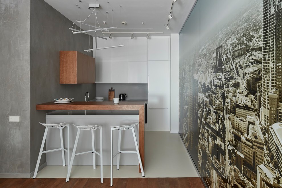 Идея дизайна: п-образная кухня-гостиная в современном стиле с плоскими фасадами, белыми фасадами, деревянной столешницей, серым фартуком, техникой под мебельный фасад, полуостровом и бежевым полом