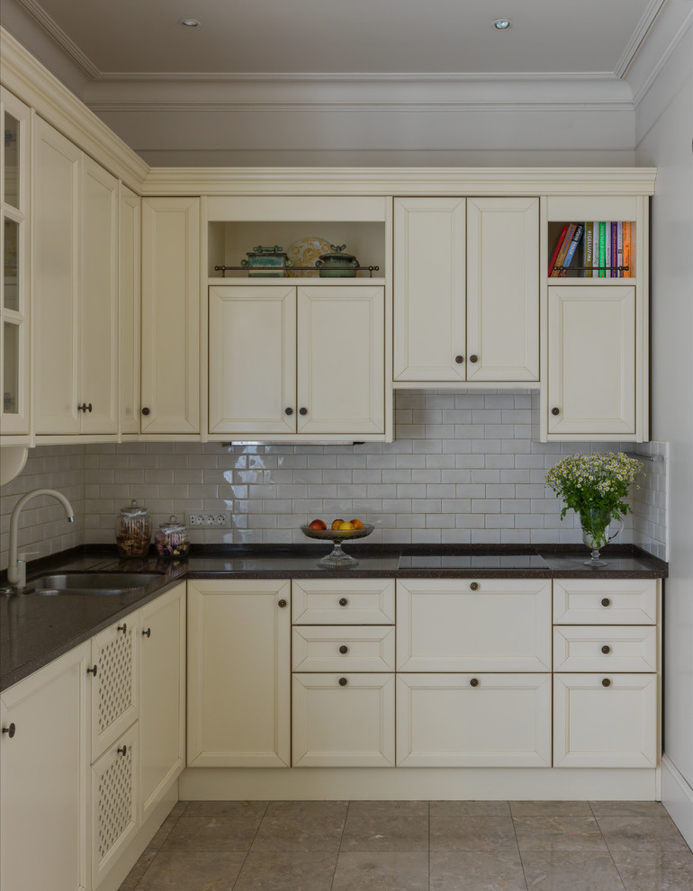 Example of a mid-sized classic l-shaped marble floor and beige floor enclosed kitchen design in Other with an undermount sink, recessed-panel cabinets, white backsplash, subway tile backsplash, paneled appliances, white cabinets and no island