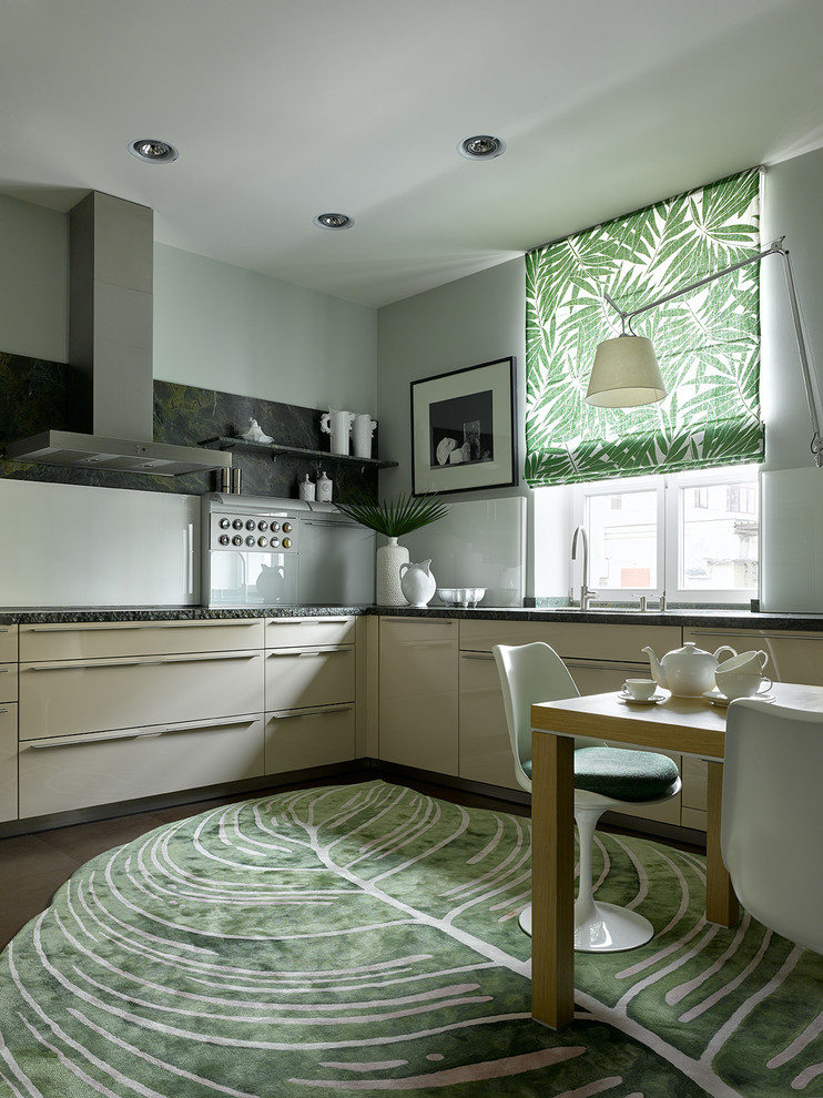 Ispirazione per una cucina a L design con ante lisce, ante beige, paraspruzzi bianco, pavimento marrone e top nero