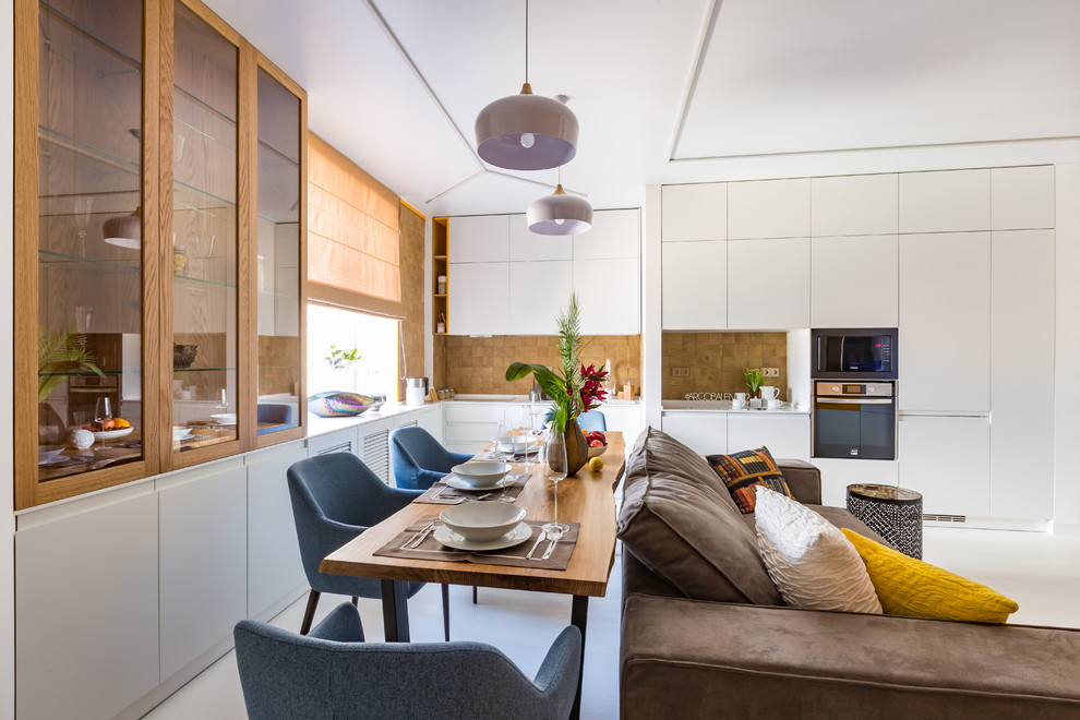 Photo of a medium sized contemporary single-wall open plan kitchen in Other with flat-panel cabinets, white cabinets, brown splashback, black appliances, white floors and white worktops.