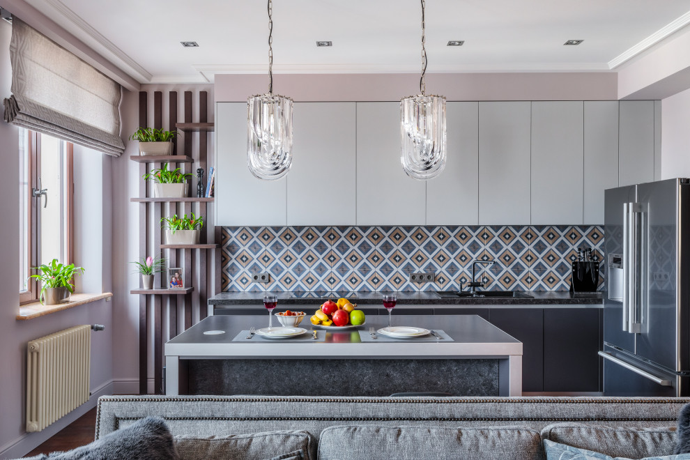 Contemporary open plan kitchen in Moscow with a built-in sink, flat-panel cabinets, grey cabinets, multi-coloured splashback, stainless steel appliances, an island and black worktops.