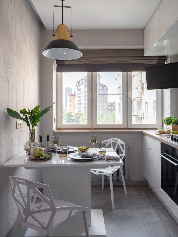 モスクワにある小さなコンテンポラリースタイルのおしゃれなキッチン (フラットパネル扉のキャビネット、白いキャビネット、黒い調理設備、グレーの床、アイランドなし、ベージュのキッチンカウンター) の写真