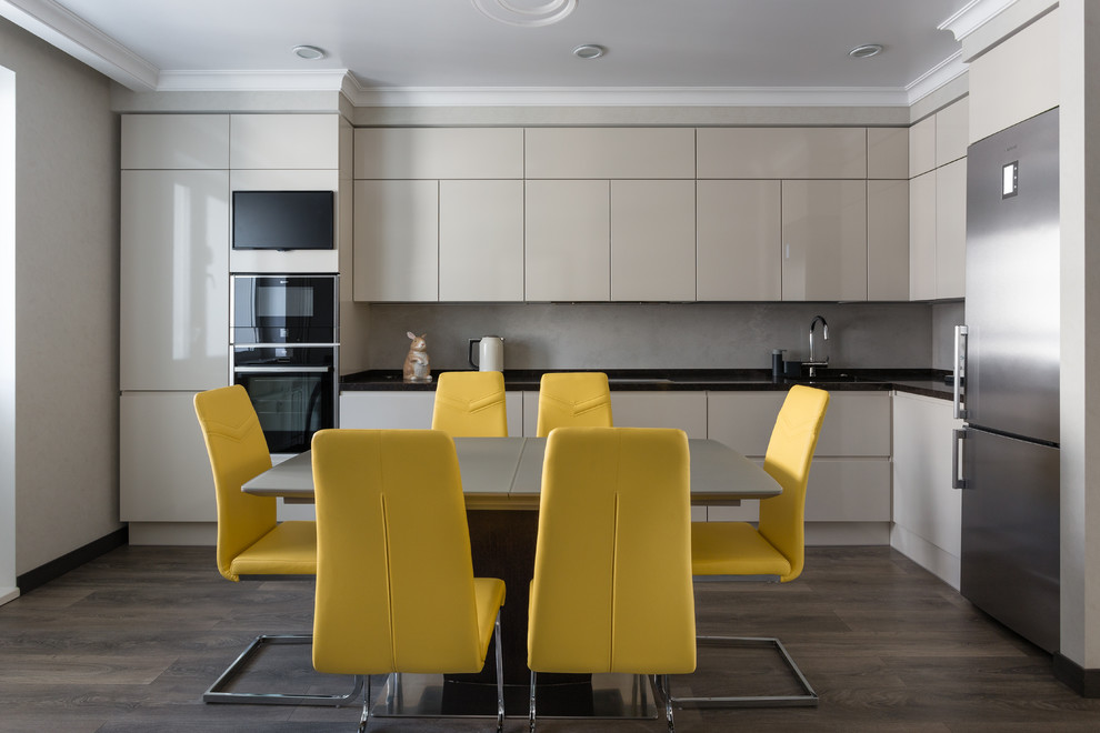 Photo of a large contemporary l-shaped kitchen/diner in Moscow with a submerged sink, flat-panel cabinets, grey cabinets, quartz worktops, grey splashback, stone slab splashback, black appliances, no island, black worktops, dark hardwood flooring and brown floors.