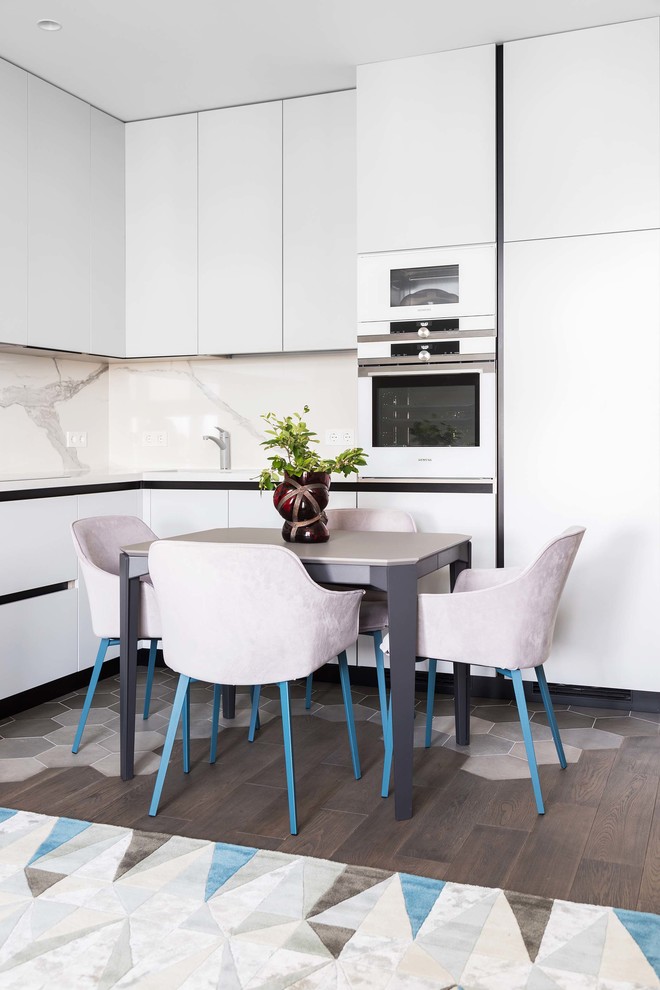 Eat-in kitchen - contemporary l-shaped dark wood floor eat-in kitchen idea in Moscow with flat-panel cabinets, white cabinets, white backsplash, white appliances, no island and white countertops