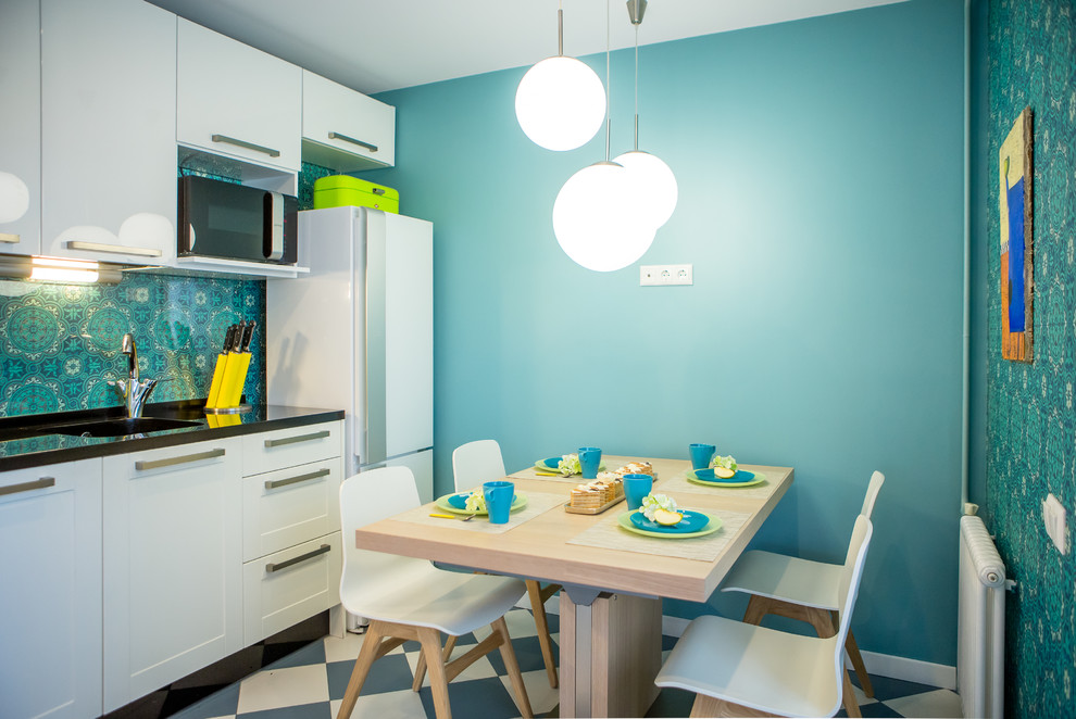 Свежая идея для дизайна: угловая кухня со шкафом над холодильником в современном стиле с фасадами в стиле шейкер, белыми фасадами, зеленым фартуком и обеденным столом без острова - отличное фото интерьера